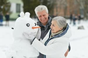 A happy senior couple building a snowman