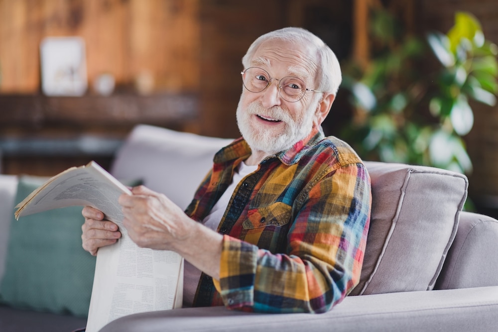 A senior man smiling while reading a newspaper