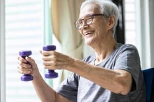 A senior woman lifting light weights at the memory care community in Elkhorn