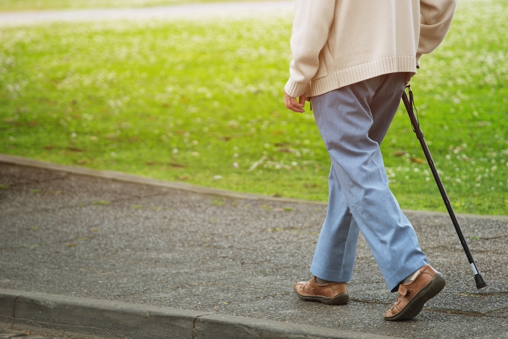 A senior man uses his cane to walk around one of the best memory care communities in Elkhorn