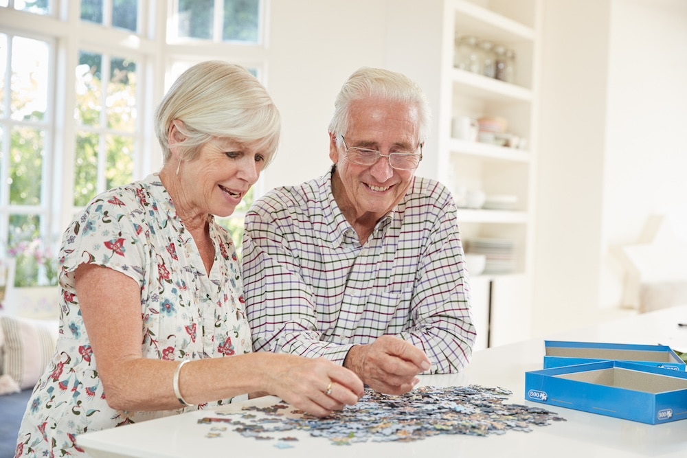 A senior couple works on a puzzle together