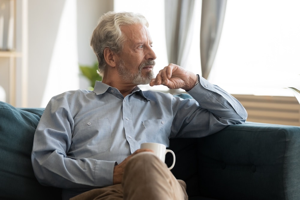 A senior man sitting on the sofa thinking about moving to memory care in Lincoln, Nebraska