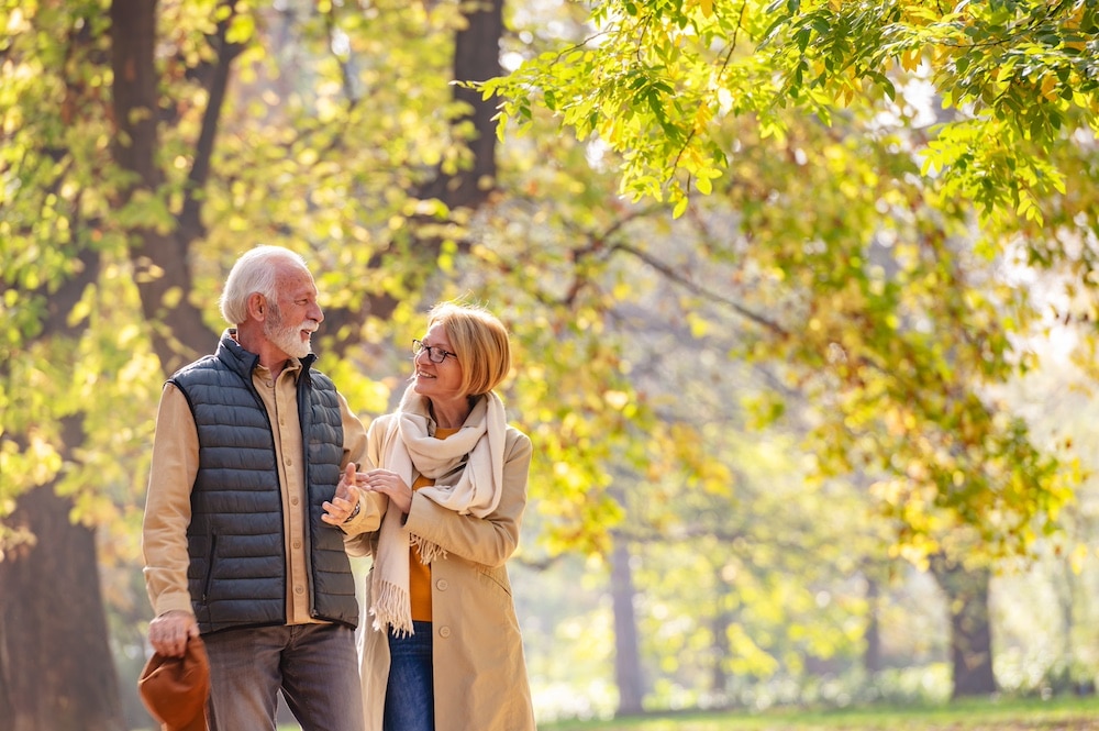 A senior couple taking a fall walk through a park