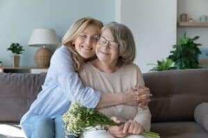 A senior woman and her daughter embrace