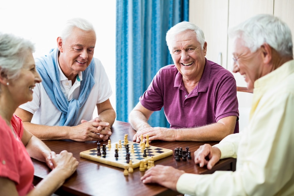 A group of senior friends playing chess together at their Iowa memory care community