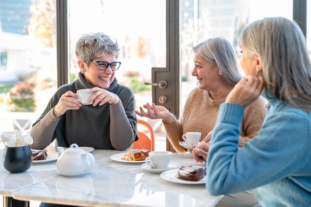 Three senior women socializing and having coffee
