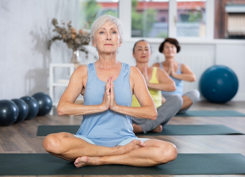 Three senior women participate in a group yoga class