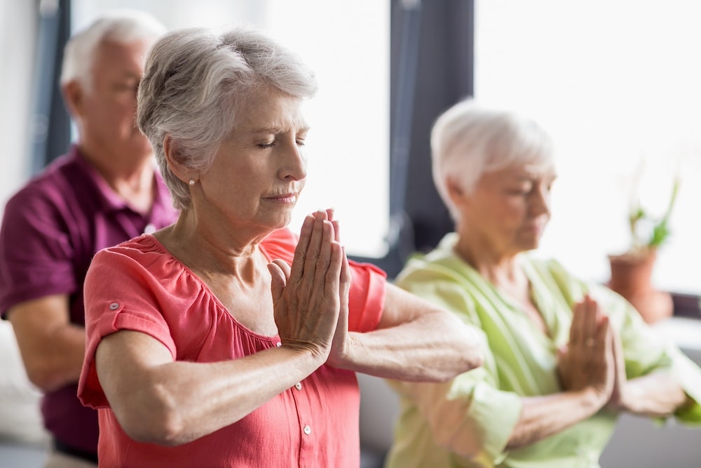 Three seniors participating in a group yoga class