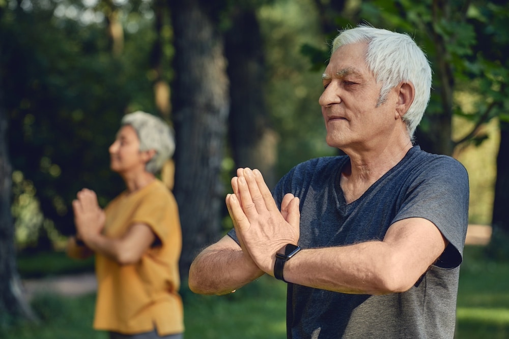 An active senior couple participates in an outdoor yoga session
